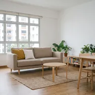 A sofa with cushions, a round coffee table and a small dining table